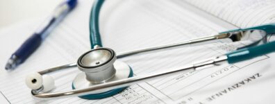 A stethoscope and pen resting on a medical report in a healthcare setting.